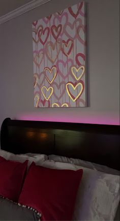 a bed with two red pillows on top of it and a painting above the headboard