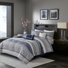 a bedroom with gray walls and bedding in front of a large window that has pictures on the wall