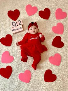 a baby is laying on a blanket with hearts around it and a sign that says love