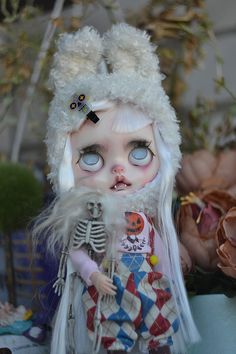 a doll with white hair and blue eyes is dressed in a costume that has feathers on it