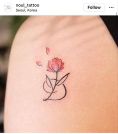 a small flower tattoo on the back of a woman's shoulder