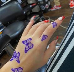 a woman's hand with purple butterflies painted on it