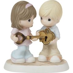 a figurine of two children holding a key and looking at each other's heart