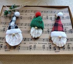 three christmas gnomes are sitting on top of sheet music and decorated with pom - poms