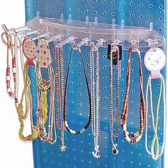 a rack with many different types of necklaces hanging from it's hooks on a blue pegboard