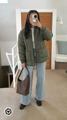 a woman taking a selfie with her cell phone in front of her face and holding a brown bag