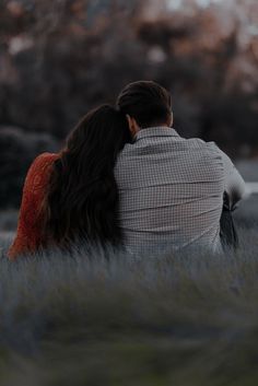 two people sitting in tall grass looking at the sky with their backs to each other