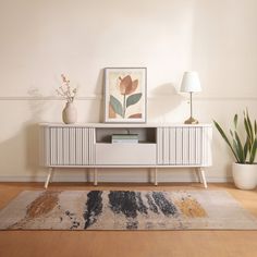 a living room with a rug, table and plant on the floor in front of it