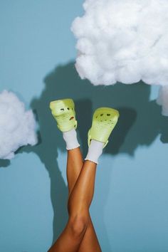 a woman's legs in white socks and green gloves with clouds above her head