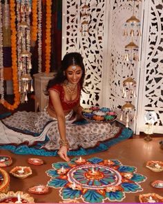 a woman sitting on the floor in front of a decorated table with plates and candles