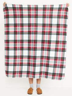 a woman is holding up a plaid blanket