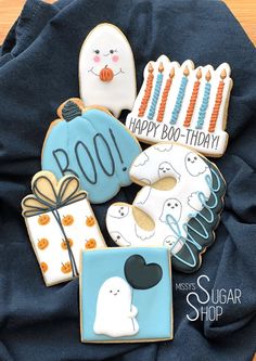 some decorated cookies are sitting on a blue cloth with happy boo - tiday written on them