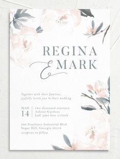 an elegant wedding card with white flowers and greenery