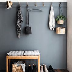 a coat rack with shoes and umbrellas hanging on the wall next to a bench