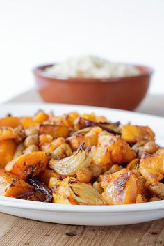 a white plate topped with potatoes and onions next to a brown bowl filled with rice