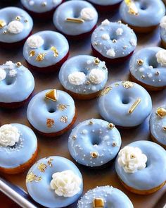 there are many blue donuts with white frosting and gold decorations on them,