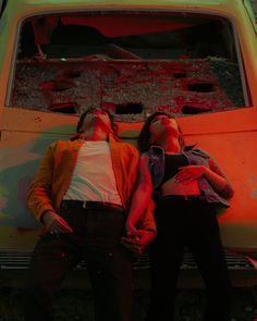 two women laying on the hood of an old car