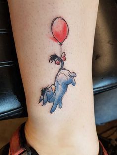 an elephant holding a red balloon tattoo on the side of a woman's leg