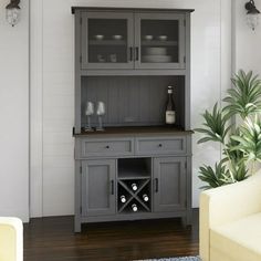 a grey hutch with wine glasses on it in the corner of a living room