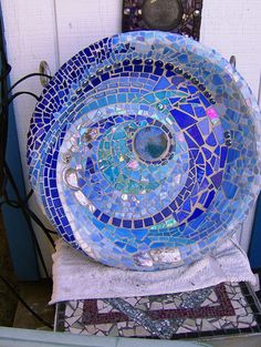 a blue bowl sitting on top of a table next to a white wall with a mirror above it