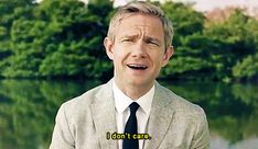 a man in a suit and tie is talking to someone on the television screen with trees behind him