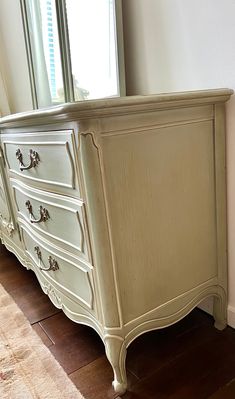 a white dresser with drawers in front of a window