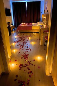 a bedroom with rose petals on the floor and lights in the hallway leading to it