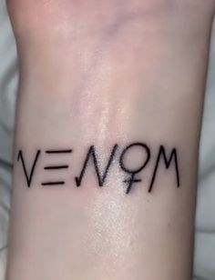 the word venom written in black ink on a woman's arm