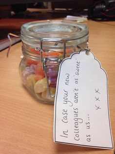 a jar filled with gummy bears sitting on top of a wooden table next to a sign