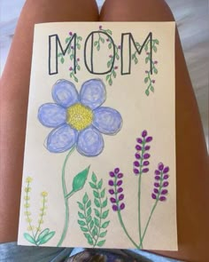 a child's drawing of a flower with the word mom written on it in front of her