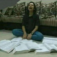 a woman is sitting on the floor with open books in front of her and laughing