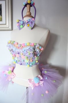 a white mannequin wearing a purple dress with colorful buttons and bows on it