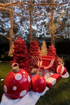 red and white christmas decorations on display in the grass with trees behind them at night