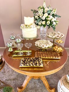 a table topped with lots of desserts on top of a wooden table next to a vase filled with flowers