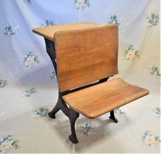 an old wooden school chair sitting on top of a white cloth covered floor next to a blue flowered wall