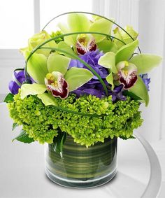 a vase filled with green and purple flowers