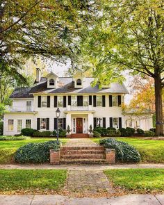 a large white house with black shutters and trees