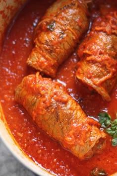 some food is in a red sauce and garnished with parsley on the side