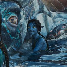 a woman with dreadlocks standing in the water next to a giant fish and another creature