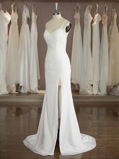 a white wedding dress on display in front of other dresses and mannequins