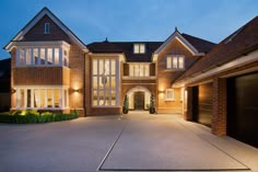 a large brick house lit up at night with lights on the windows and garage doors