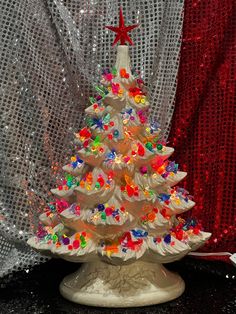 a christmas tree made out of candy on a table next to a red and white curtain