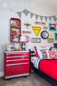 a bedroom with a red dresser and lots of pictures on the wall above it, along with a bed