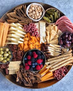 an assortment of cheeses, crackers, nuts and berries on a platter