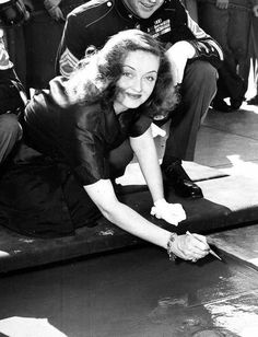 a woman kneeling down on the ground in front of a group of uniformed men and women