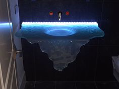 a bathroom with a sink that is lit up in the dark and has blue lights on it