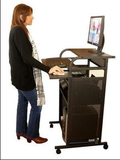 a woman standing in front of a computer desk with a monitor and keyboard on it