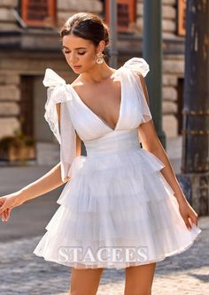 a woman in a short white dress is walking down the street with her hand on her hip