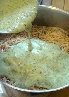 a pot filled with pasta and sauce being poured over it on top of the noodles