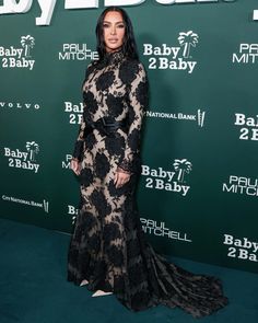 a woman in a black and white dress standing on a green carpet with the words baby2baby